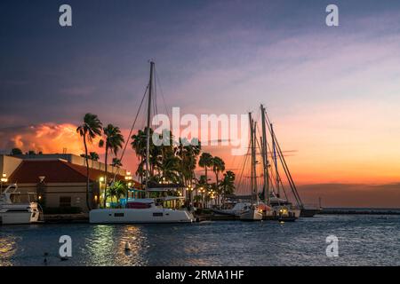 Oranjestad Aruba vista al tramonto con barche, oceano e palme Foto Stock