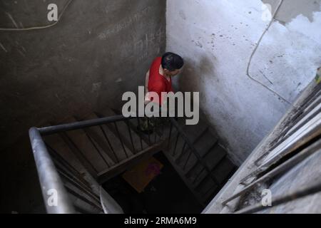 (140620) -- YINCHUAN, 20 giugno 2014 (Xinhua) -- Un residente cammina giù le scale all'interno di una villa del nuovo villaggio di Wulitai a Yinchuan, regione autonoma Ningxia Hui della Cina nord-occidentale, 10 giugno 2014. Ci sono oltre 30 ville nel nuovo villaggio di Wulitai con un terzo incompleto a causa del default dei pagamenti per la costruzione. Quelle ville ora sono affittate ai lavoratori migranti. Una villa di 200 metri quadrati è stata separata in diverse stanze, e l'affitto di ognuna è di circa 300 yuan (circa 48,18 dollari USA). Per i lavoratori migranti che non hanno accesso a bungalow economici o non possono permettersi appartamenti, questa camera è una buona risoluzione Foto Stock