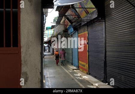 (140624) -- SRINAGAR, 24 giugno 2014 (Xinhua) -- Una donna del Kashmir cammina con sua figlia attraverso un mercato chiuso durante uno sciopero a Srinagar, la capitale estiva del Kashmir controllato dagli indiani, il 24 giugno 2104. La vita normale nelle aree a maggioranza musulmana del Kashmir controllato dagli indiani, compresa la città di Srinagar, è stata colpita martedì a causa di un arresto separatista. La richiesta di chiusura è stata data dal gruppo separatista della regione per protestare contro l'uccisione di un giovane quando le truppe indiane spararono contro i manifestanti lunedì. Le proteste scoppiarono a Krank Shivan nella città di Sopore, circa 54 km a nord-ovest della città di Srinagar Foto Stock