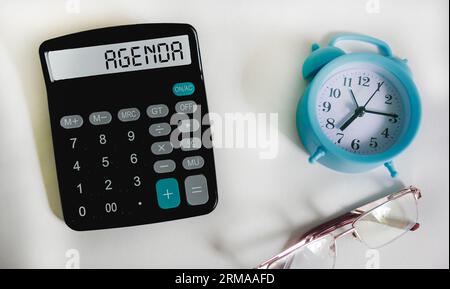 Simbolo del programma. Calcolatrice con parola Agenda Concept su sfondo bianco con orologio e occhiali. Foto Stock