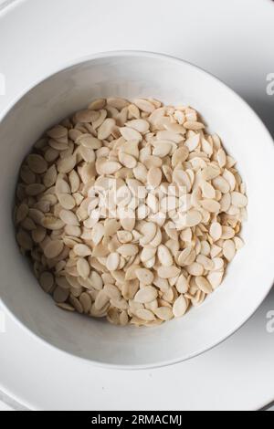 vista dall'alto dei semi di egusi nigeriani in una ciotola bianca, vista dall'alto dei semi di melone sgusciati in una ciotola, dei semi di melone nigeriani e dei semi di zucca per cucinare Foto Stock