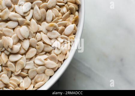 vista dall'alto dei semi di egusi nigeriani in una ciotola bianca, vista dall'alto dei semi di melone sgusciati in una ciotola, dei semi di melone nigeriani e dei semi di zucca per cucinare Foto Stock