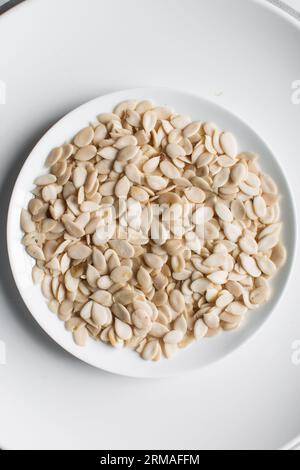 vista dall'alto dei semi di egusi nigeriani in una ciotola bianca, vista dall'alto dei semi di melone sgusciati in una ciotola, dei semi di melone nigeriani e dei semi di zucca per cucinare Foto Stock