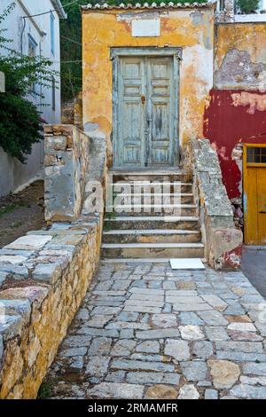 Ingresso di una bella vecchia casa dai colori vivaci ma invecchiati sulle pareti usurate, nell'isola di Idra, in Grecia, in Europa. Foto Stock