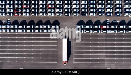 Vista aerea direttamente sopra le file di auto di nuova costruzione nell'industria automobilistica su un molo commerciale pronto per essere caricato per l'esportazione e l'importazione Foto Stock