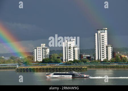 Uber Boat in Thames Clipper River bus, battello Cyclone Clipper sul Tamigi a Londra sotto tempesta con un arcobaleno Foto Stock