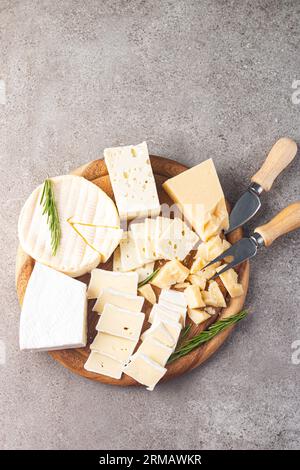 Tavola di legno con vari formaggi e olive. Brie. Camembert. Parmigiano, feta, formaggio blu. Formaggio italiano, francese. Foto Stock