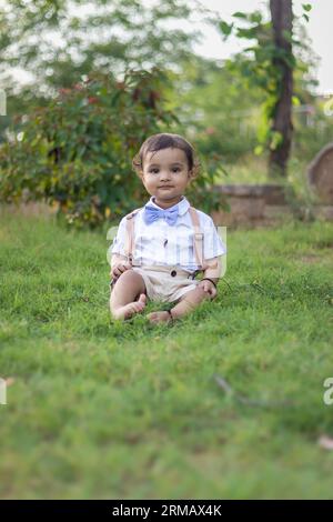 bambino piccolo isolato con un'espressione facciale innocente all'aperto da un'angolazione diversa durante il giorno Foto Stock