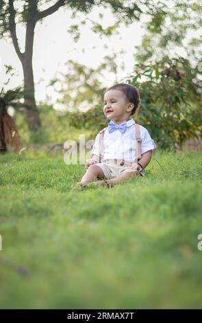 bambino piccolo isolato con un'espressione facciale innocente all'aperto da un'angolazione diversa durante il giorno Foto Stock