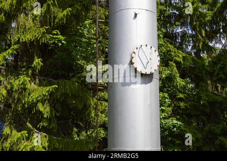 Grande colonna serbatoio industriale in acciaio inox brillante con portello rotondo pieghevole, pozzetto d'ispezione con bulloni, dadi e prigionieri sullo sfondo di g Foto Stock