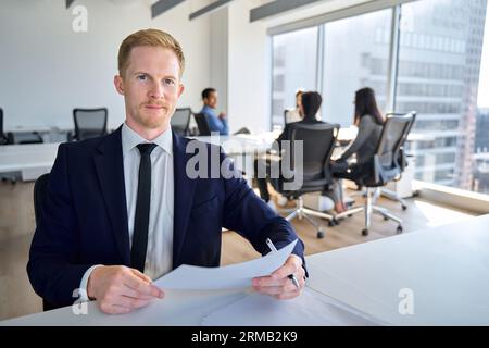 Uomo d'affari sicuro e felice, direttore di banca seduto in ufficio con documenti in mano. Foto Stock