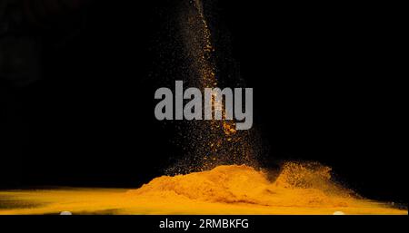 Curcuma, curcuma longa, polvere che cade su sfondo nero, Indian Spice Foto Stock
