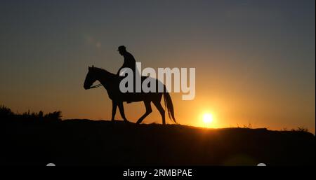 Uomo sul suo Cavallo della Camargue, che galoppa all'alba, Manadier a Saintes Marie de la Mer in Camargue, nel sud della Francia, Cow Boy Foto Stock