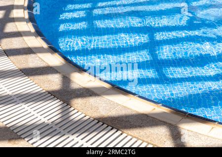 La luce e le ombre si raddoppiano sull'acqua nella piscina all'aperto Foto Stock