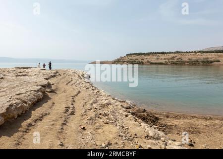 I turisti di Salty Rocks si trovano sulla costa del Mar morto in Giordania Foto Stock