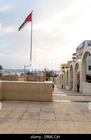 Bandiera della Giordania su un'asta di bandiera nella rivolta araba, vista attraverso le strette strade di Aqaba in Giordania Foto Stock