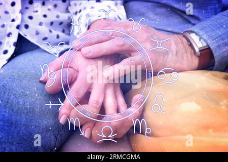 Relazioni e oroscopo. Ruota zodiacale e foto di uomo e donna maturi che si tengono per mano, primo piano Foto Stock