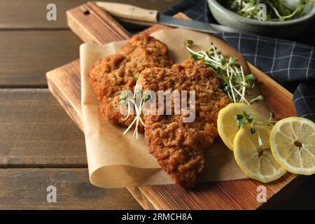 Gustosi schnitzels serviti con limone e microgreen su un tavolo di legno, primo piano Foto Stock