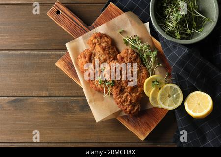 Gustosi schnitzels serviti con limone e microgreen su un tavolo di legno, piatti. Spazio per il testo Foto Stock