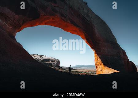 Una persona in un cancello ad arco aperto incorniciato da una splendida catena montuosa nel Parco Nazionale degli Arches Foto Stock