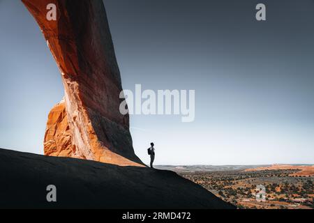 Una persona vicino a un cancello ad arco aperto incorniciato da una splendida catena montuosa nel Parco Nazionale degli Arches Foto Stock