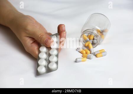 Pillole in un palmo di mano femminile sul letto. Concetto di farmaco, vitamine o pillola del sonno Foto Stock