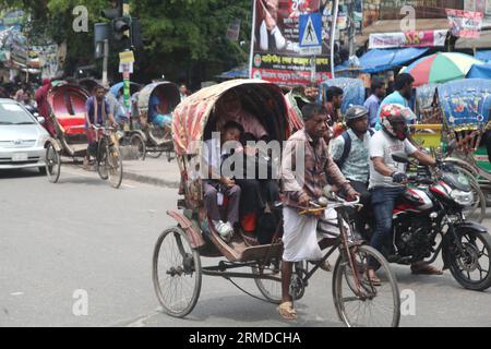 Dhaka, Bangladesh. 27 agosto 2023. Una vista generale mostra che gli estrattori di risciò trasportano i loro clienti nel traffico sulla New Market Road a DH Foto Stock