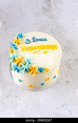 Torta bento alla moda con un'iscrizione blu-gialla in ucraino "buon compleanno" su sfondo chiaro. Torta di compleanno, torta Bento per due Ukrai Foto Stock