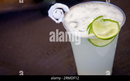 Margarita in una tazza di plastica guarnita con un lime Foto Stock