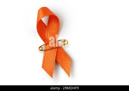 Nastro arancione con spilla di sicurezza su sfondo bianco - concetto di sensibilizzazione alla leucemia, associazione del cancro ai reni, sclerosi multipla e abuso di animali Foto Stock