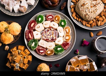 Dolci mediorientali, delizie turche e caffè su sfondo nero. Assortimento di dessert arabi, rahat lokum, halva, sherber, pismaniye con noci e. Foto Stock