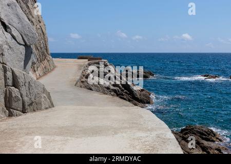 Tranquilla strada costiera lungo le coste rocciose con vista sul mare Foto Stock