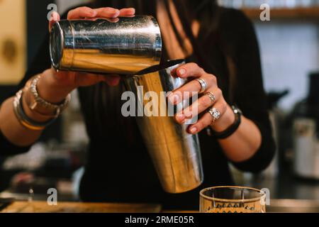 La giovane barwoman prepara un cocktail alcolico al bar. Foto Stock