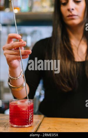 La giovane barwoman prepara un cocktail alcolico al bar. Foto Stock
