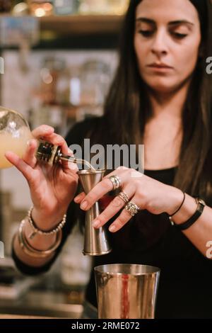 La giovane barwoman prepara un cocktail alcolico al bar Foto Stock