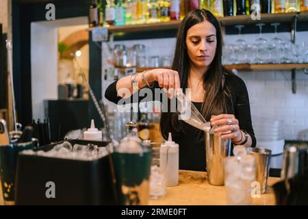 La giovane barwoman prepara un cocktail alcolico al bar Foto Stock