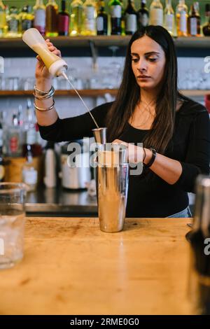 La giovane barwoman prepara un cocktail alcolico al bar Foto Stock