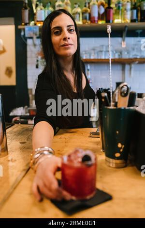 La giovane barwoman prepara un cocktail alcolico al bar Foto Stock