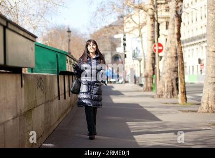 Una bella turista bruna a Parigi che cammina accanto alle scatole dei librai Foto Stock