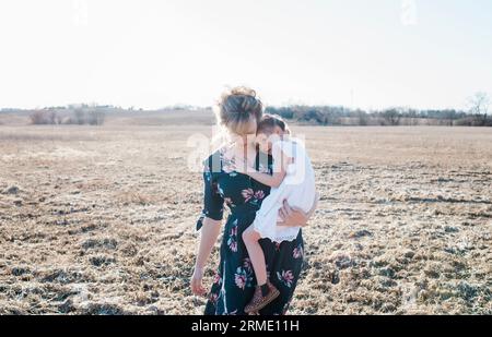 madre che tiene sua figlia che cammina in un deposito al tramonto Foto Stock