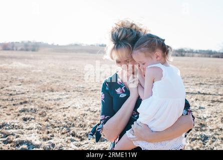 madre che coccola sua figlia mentre ride Foto Stock