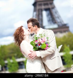 Matrimonio a Parigi. Felice coppia di sposi che si baciano vicino alla Torre Eiffel Foto Stock