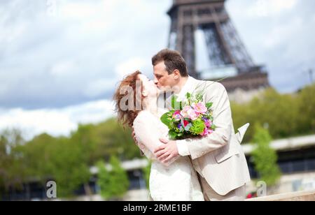 Matrimonio a Parigi. Felice coppia di sposi che si baciano vicino alla Torre Eiffel Foto Stock