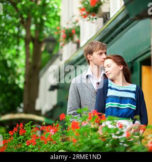 Uomo e donna insieme sul balcone della loro casa o hotel con geranio fiorito e una bella vista Foto Stock