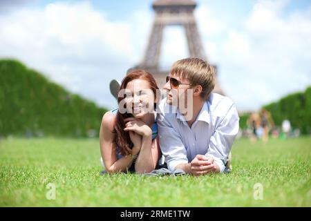 Primo piano di una felice coppia positiva stesa sull'erba a Parigi Foto Stock