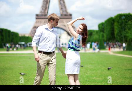 Primo piano di una felice coppia positiva che balla vicino alla Torre Eiffel Foto Stock