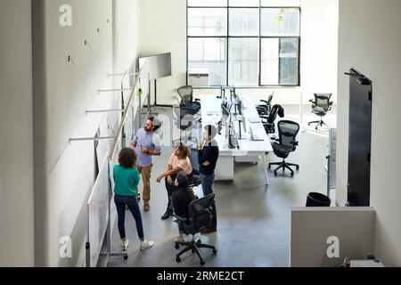 Vista ad alto angolo dei colleghi che discutono su una lavagna bianca durante una riunione in ufficio Foto Stock