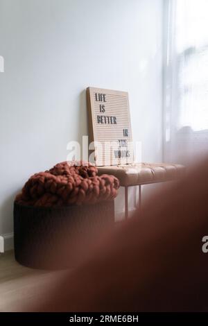 Una coperta a maglia ruggine in un cesto accanto a un cestino di legno Foto Stock