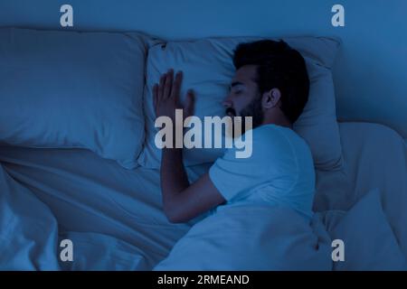 Tranquillo e bello giovane indiano che dorme in un comodo letto da solo a casa Foto Stock