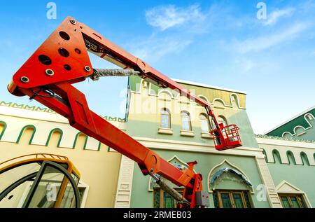 Lavoratori che dipingono pareti esterne su veicoli di lavoro aerei Foto Stock